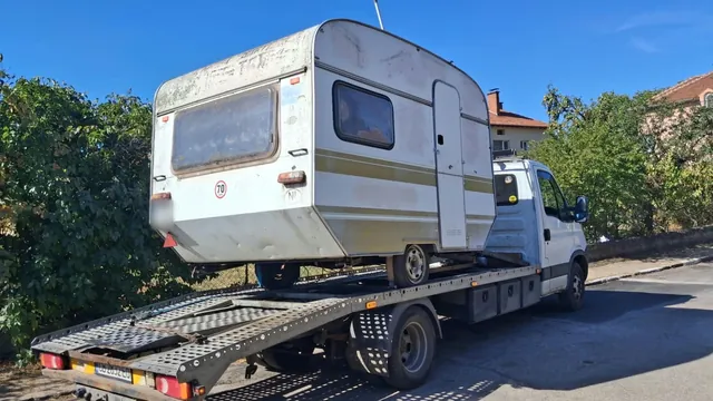 Каравана, закрепена на платформата на репатрака Iveco Daily, погледната отстрани
